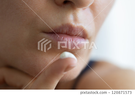 Woman with cream for lips on her finger. Closeup, selective focus. 120871573