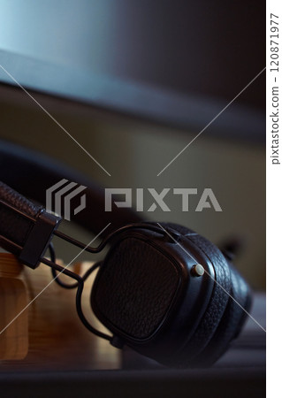 Stylish black headphones resting on a wooden desk 120871977