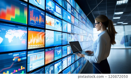 Woman working on laptop while chucking monitor screen on wall 120872050
