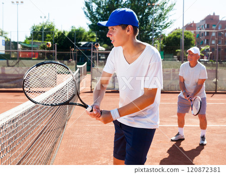 Grandfather and grandson playing tennis court 120872381