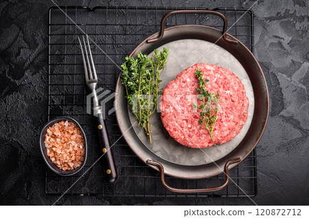 Stack of Raw meat patties, cutlets, chopped meat for burgers in stell tray with herbs. black background. top view 120872712