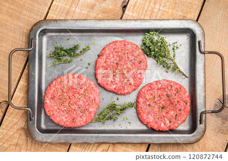 Raw hamburger minced meat patties for burgers with herbs on tray. wooden background. top view 120872744