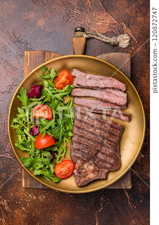 Roast dry aged Top Sirloin beef steak on plate with salad. brown background. top view 120872747