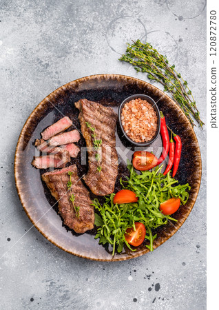 BBQ Grilled skirt or machete Steak, beef meat on a plate with salad. grey background. top view 120872780