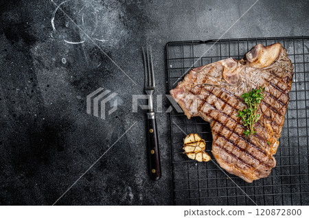 Grilled T-bone or Porterhouse beef meat Steak on a rack. Black background. Top view. Copy space 120872800