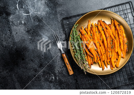 Baked sweet potato fries on a plate with herbs. Black background. Top view. Copy space Baked sweet potato fries on a plate with herbs. Black background. Top view. Copy space 120872819
