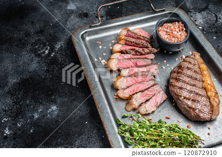 Fried and sliced Top sirloin steak, Grilled cup rump beef meat steak on a steel serving tray with spices. Black background. Top view. Copy space Fried and sliced Top sirloin steak, Grilled cup rump beef meat steak on a steel serving tray with spices. Black background. Top view. Copy space 120872910