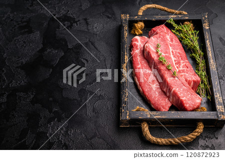 Raw skirt or machete Steak, beef meat in wooden tray with herbs. black background. top view 120872923