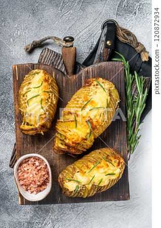 Roasted hasselback potatoes with cheese, garlic, thyme and rosemary. White background. Top view Roasted hasselback potatoes with cheese, garlic, thyme and rosemary. White background. Top view 120872934