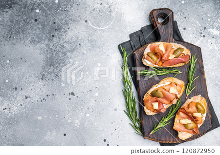 Tapa with Jamon cured ham, parmesan cheese and olives. grey background. top view 120872950