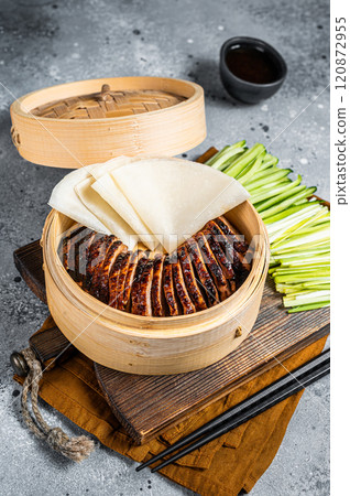 Peking Duck in bamboo steamer served with cucumber, green onion, and wheaten chinese pancakes and sauce Hoysin. Gray background. Top view 120872955