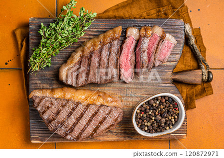 BBQ Roast brazilian Picanha steak, cup rump beef meat steak on a wooden serving board. Orange background. Top view 120872971