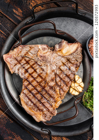 BBQ Grilled T-bone or Porterhouse beef meat Steak on a steel tray with herbs. Wooden background. Top view BBQ Grilled T-bone or Porterhouse beef meat Steak on a steel tray with herbs. Wooden background. Top view 120872993