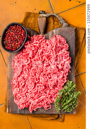 Fresh Raw Mince, Ground beef and pork meat on a butcher board. Orange background. Top view 120872999
