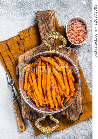 Roasted sweet potato french fries in a skillet with herbs. White background. Top view Roasted sweet potato french fries in a skillet with herbs. White background. Top view 120873005