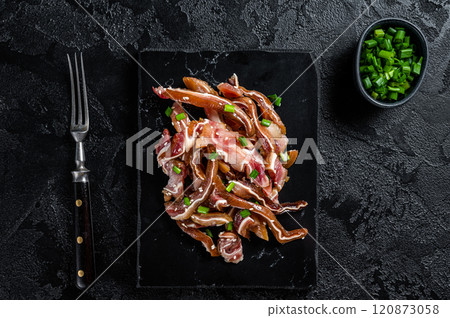 Fried pig ears with sesame seeds and green onions. Fried pork ears in korean style with spicy sauce. Black background. Top view 120873058