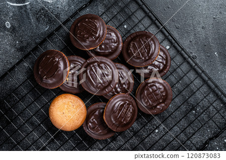 Jaffa Cakes, Cookies covered with dark chocolate and filled with orange marmalade. Black background. Top view 120873083