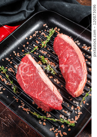 Sirloin steak or brazilian Picanha, raw marbled beef meat with on a grill skillet. Dark background. Top view Sirloin steak or brazilian Picanha, raw marbled beef meat with on a grill skillet. Dark background. Top view 120873096