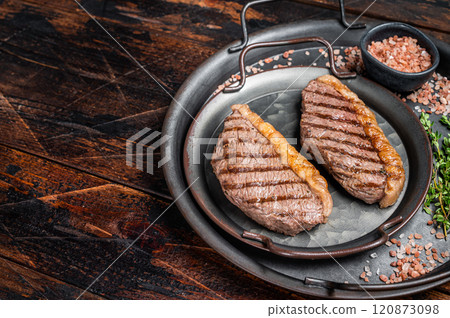 BBQ Grilled top sirloin steak, cup rump beef meat steak in a steel tray. Wooden background. Top view. Copy space BBQ Grilled top sirloin steak, cup rump beef meat steak in a steel tray. Wooden background. Top view. Copy space 120873098