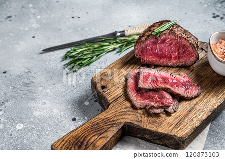 Roasted Rump beef steak sliced on a wooden cutting board. Gray background. Top view. Copy space 120873103