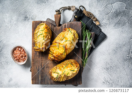 Roasted hasselback potatoes with cheese, garlic, thyme and rosemary. White background. Top view Roasted hasselback potatoes with cheese, garlic, thyme and rosemary. White background. Top view 120873117