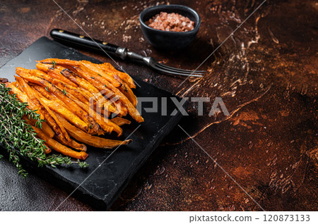 Fried sweet potato french fries on a board with thyme. Dark background. Top view. Copy space Fried sweet potato french fries on a board with thyme. Dark background. Top view. Copy space 120873133