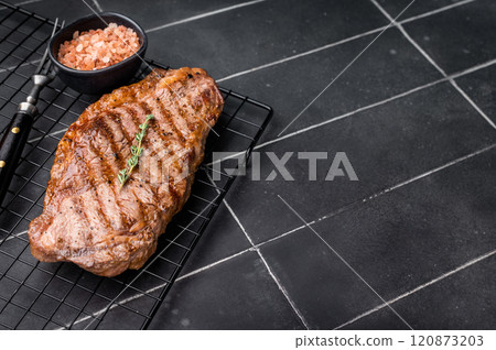 Grilled Striploin steak, New York strip beef meat steak on a rack. black background. top view 120873203