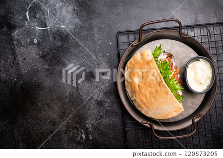 Gyros with grilled chicken meat, salad, tomato, onion, tzatziki in pita bread. black background. top view 120873205