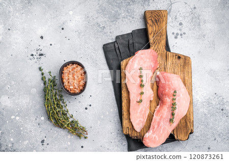 Ready for cooking pork loin fillets, raw tenderloin meat on a wooden board. Gray background. top view Ready for cooking pork loin fillets, raw tenderloin meat on a wooden board. Gray background. top view 120873261