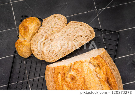 Handcrafted sliced tartin bread on steel rack. Black background. Top view Handcrafted sliced tartin bread on steel rack. Black background. Top view 120873278