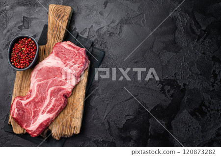 Uncooked Raw Chuck eye roll steak, prime beef meat on wooden board. black background. top view 120873282
