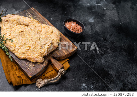 Wiener breaded raw pork Schnitzel, meat steak on a wooden board. black background. top view Wiener breaded raw pork Schnitzel, meat steak on a wooden board. black background. top view 120873298