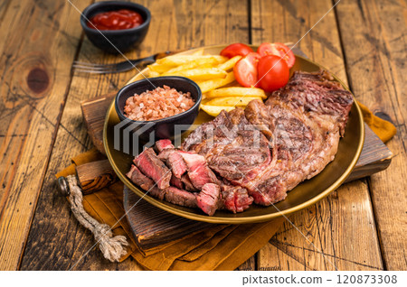 A juicy Grilled Chuck eye roll steak and garnish with french fry on a plate. wooden background. top view 120873308