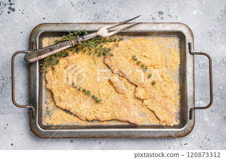 Cooking of Raw breaded Wiener Schnitzel steak in steel tray. gray background. top view 120873312