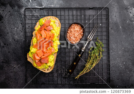 Toast with salty salmon, trout slices, avocado and red caviar. black background. top view Toast with salty salmon, trout slices, avocado and red caviar. black background. top view 120873369
