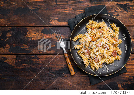 Italian Carbonara pasta topped with crispy bacon bits in a plate. Wooden background. Top view Italian Carbonara pasta topped with crispy bacon bits in a plate. Wooden background. Top view 120873384