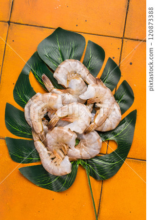 Uncooked Raw white shrimps prawns. Top view. Orange background Uncooked Raw white shrimps prawns. Top view. Orange background 120873388