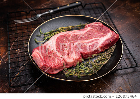 Chuck eye roll steak, raw marbled beef meat with herb for cooking. brown background. top view 120873464