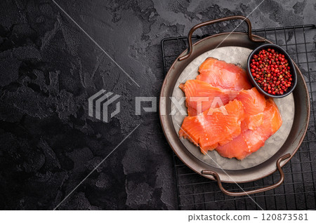 Salty salmon, trout fillet slices on steel tray. black background. top view Salty salmon, trout fillet slices on steel tray. black background. top view 120873581