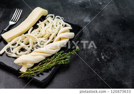 Assortiment of Traditional Caucasian Chechil white cheese on black board, top view. 120873633