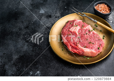 Raw Rib eye steak with herbs and spice in plate, fresh beef meat. black background. top view Raw Rib eye steak with herbs and spice in plate, fresh beef meat. black background. top view 120873664