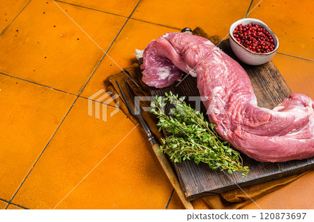 Fresh Raw pork tenderloin fillet meat on a wooden board with thyme. Orange background. Top view. Copy space Fresh Raw pork tenderloin fillet meat on a wooden board with thyme. Orange background. Top view. Copy space 120873697