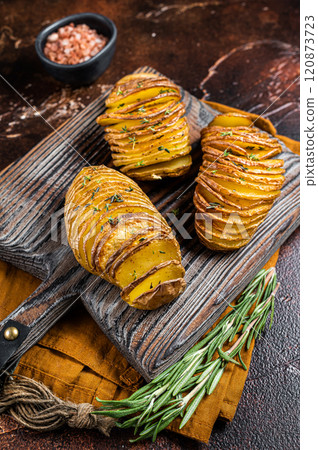 Roasted Hasselback Potato with Fresh thyme and rosemary. Dark background. Top view 120873723