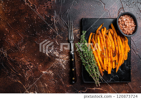 Fried sweet potato french fries on a board with thyme. Dark background. Top view. Copy space Fried sweet potato french fries on a board with thyme. Dark background. Top view. Copy space 120873724