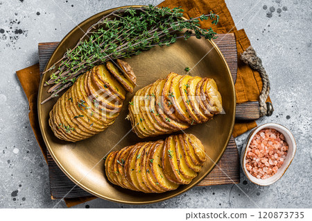 Baked Hasselback Potato with Fresh thyme and rosemary. Gray background. Top view 120873735