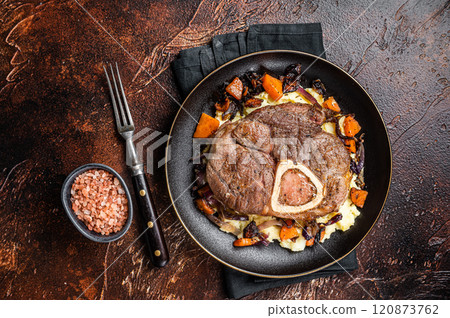 Osso buco cross cut veal shank with mashed potato on a plate. Dark background. Top view 120873762