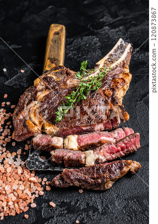 Dry aged grilled Tomahawk or cowboy beef meat steak on a meat cleaver. Black background. Top view Dry aged grilled Tomahawk or cowboy beef meat steak on a meat cleaver. Black background. Top view 120873867