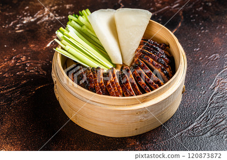 Peking Duck in bamboo steamer served with cucumber, green onion, and wheaten chinese pancakes. Dark background. Top view 120873872