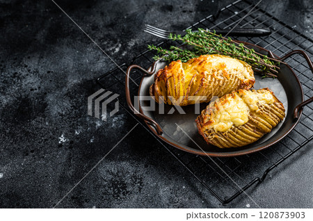 Baked hasselback potatoes with cheese, garlic, thyme and rosemary. Black background. Top view. Copy space Baked hasselback potatoes with cheese, garlic, thyme and rosemary. Black background. Top view. Copy space 120873903