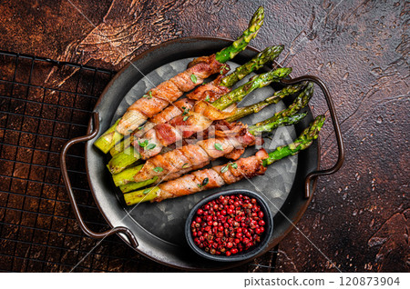 Baked Prosciutto wrapped green asparagus. Dark background. Top view Baked Prosciutto wrapped green asparagus. Dark background. Top view 120873904